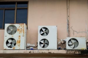 three old, rusty air conditioner units